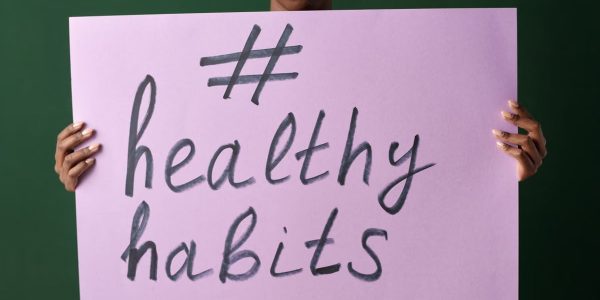 Person holding a "#healthyhabits" sign, emphasizing wellness.