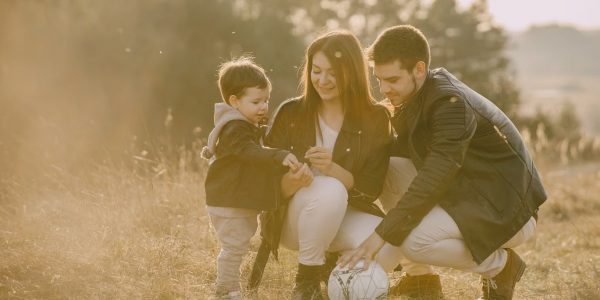 A cheerful family bonding outdoors with a soccer ball, enjoying a sunny day in the grass.
