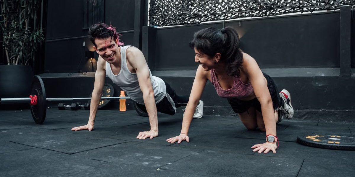 Man and woman doing pushups while smiling during a workout inside a Mexico City gym.