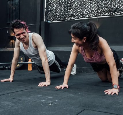 Man and woman doing pushups while smiling during a workout inside a Mexico City gym.