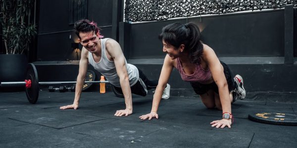 Man and woman doing pushups while smiling during a workout inside a Mexico City gym.